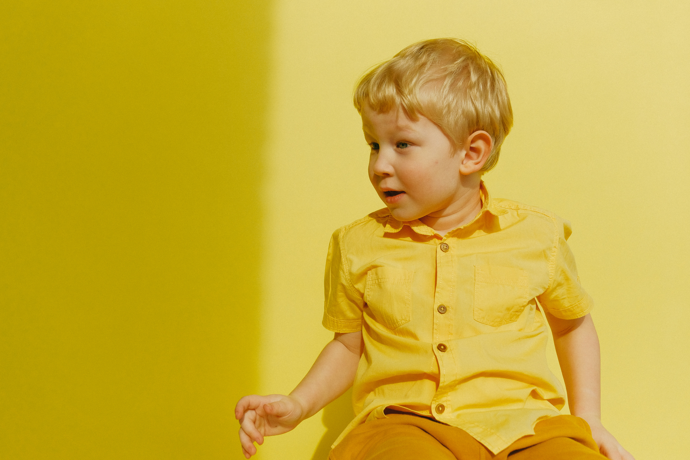 Child in Yellow Button Up Shirt Sitting Near Wall